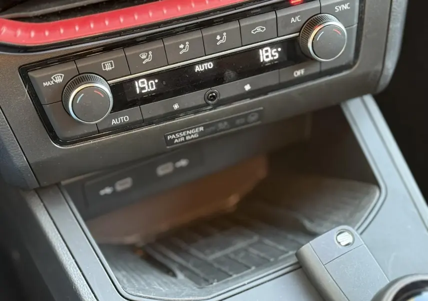 Détail de la console centrale du SEAT IBIZA TSI 115 FR 2025 montrant la climatisation automatique bi-zone et le chargeur à induction noir.