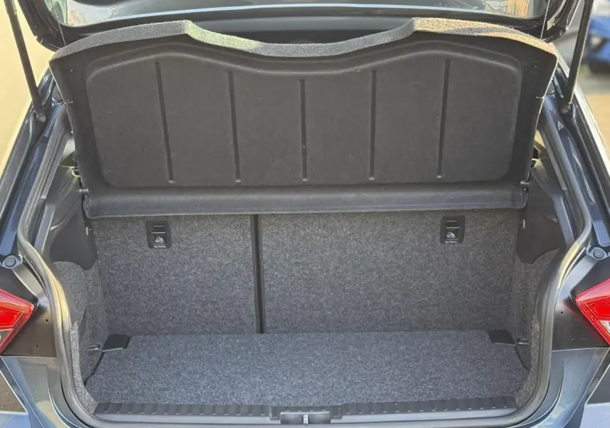 Coffre ouvert vu de l'arrière d'une SEAT IBIZA gris magnétique avec intérieur de coffre en tissu gris.