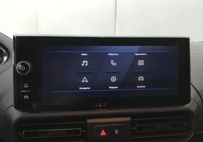 Écran tactile central du Peugeot Partner 2025 affichant les options radio, téléphone, navigation et réglages, intérieur noir.