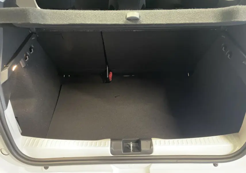 Vue intérieure du coffre ouvert d'une Dacia Sandero TCe 90 Stepway blanc glacier, montrant l'espace de rangement vide.