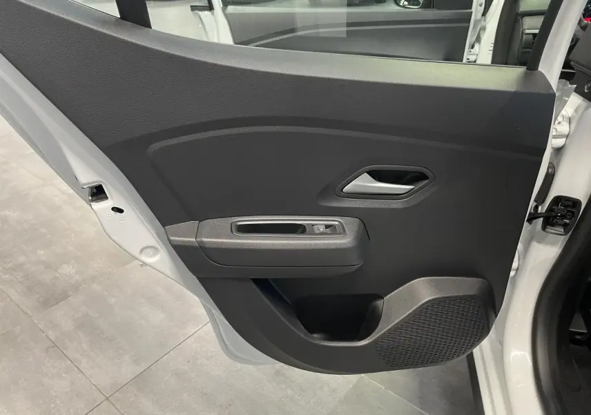 Vue intérieure de la porte arrière gauche noire avec poignée grise et bouton de lève-vitre sur Dacia Sandero Blanc Glacier.