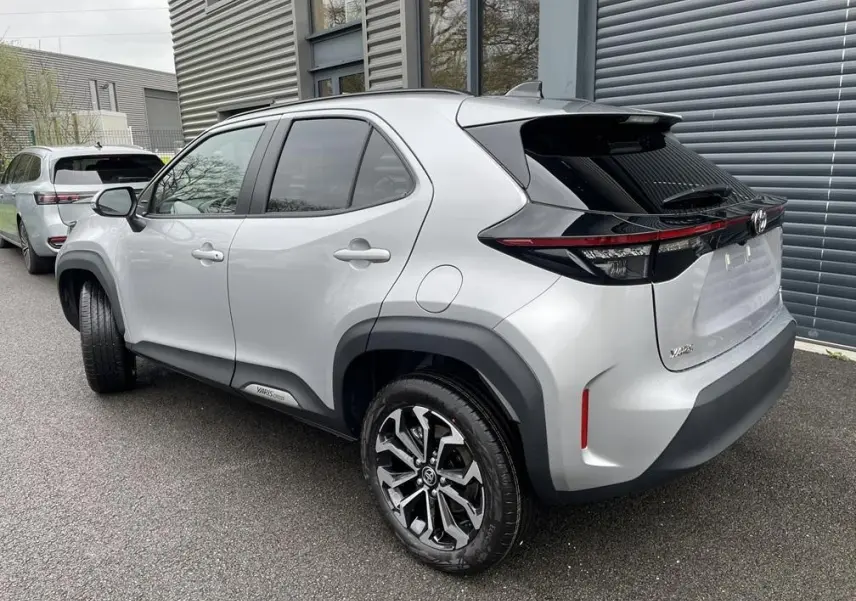 Toyota Yaris Cross gris clair vue 3/4 arrière droit, avec jantes alliage et feux arrière LED noirs.