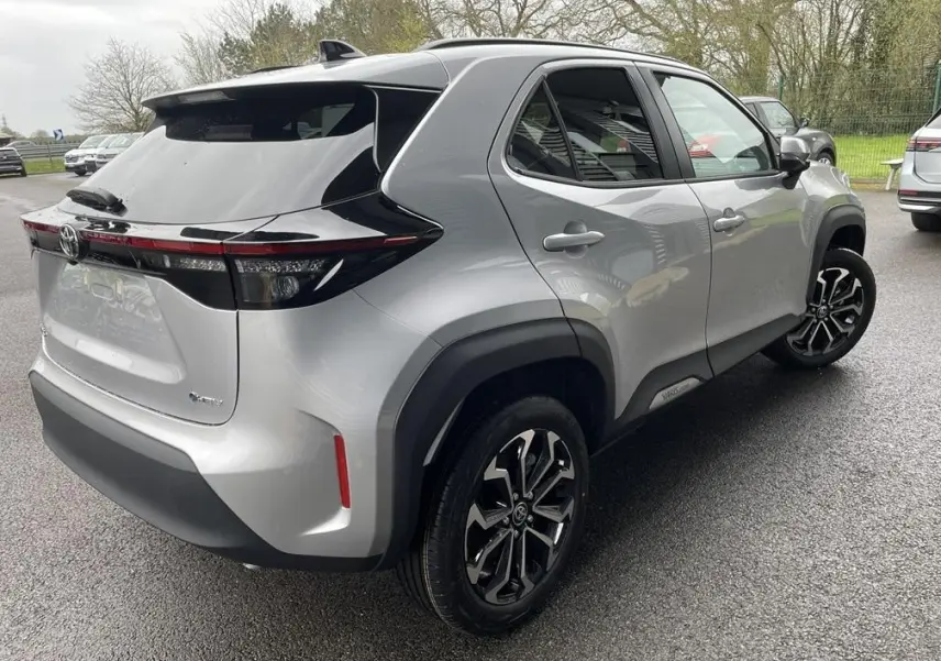 Vue 3/4 arrière droite d'une Toyota Yaris Cross gris clair avec toit noir et jantes alliage noires.
