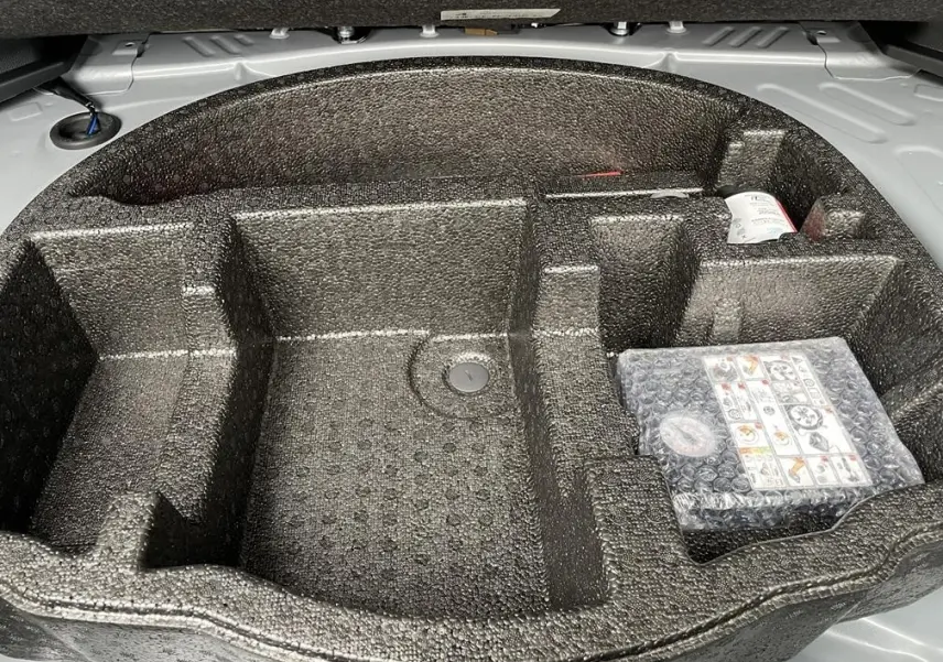 Vue rapprochée du rangement en mousse noire dans le coffre gris clair de la Toyota Yaris Cross 2026.