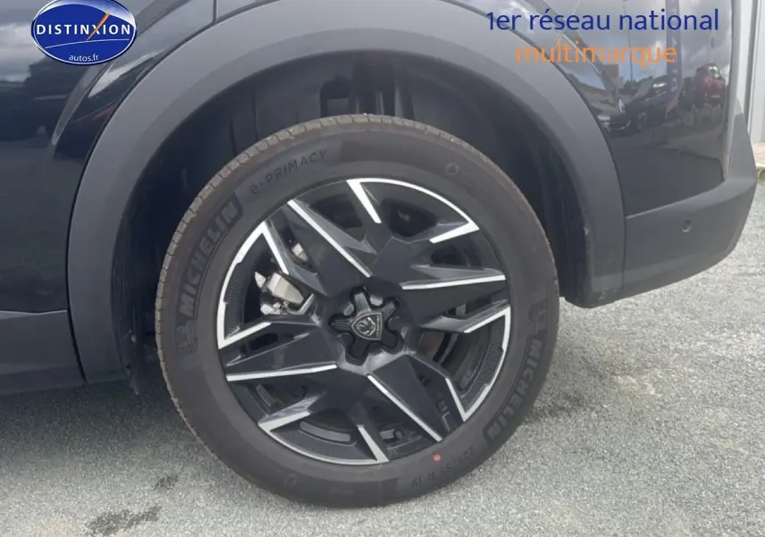 Gros plan sur la roue avant droite noire du Peugeot 5008 Hybrid 145 allure e-dcs6 avec jante alu bicolore.