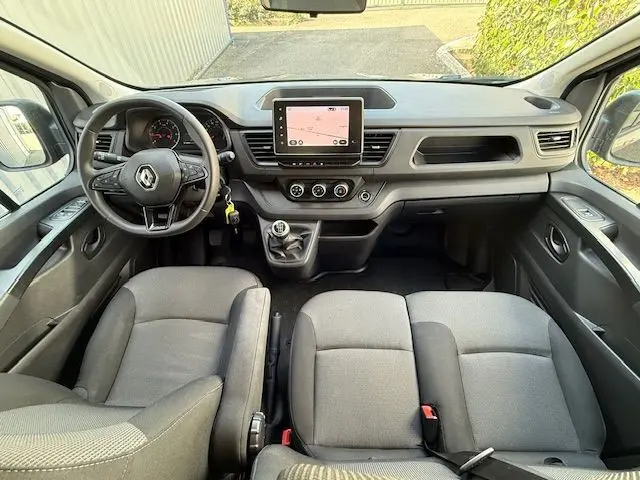 Vue intérieure avant du Renault Trafic Combi gris comète 2022, montrant le tableau de bord avec écran tactile et boîte manuelle.