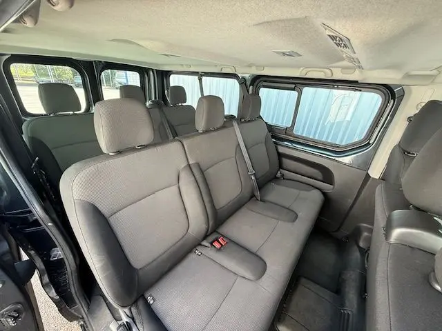 Vue intérieure côté droit du Renault Trafic Combi gris comète, montrant les sièges arrière en tissu et les ceintures de sécurité.