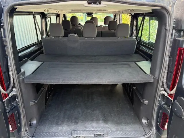 Vue arrière ouverte du Renault Trafic Combi gris comète 2022, montrant l'espace intérieur et les sièges 9 places.