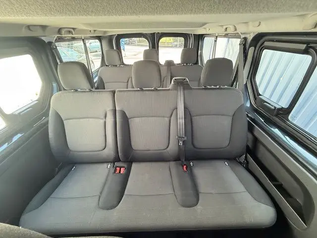 Vue intérieure arrière du Renault Trafic Combi 9 places, sièges gris foncé avec ceinture centrale visible.