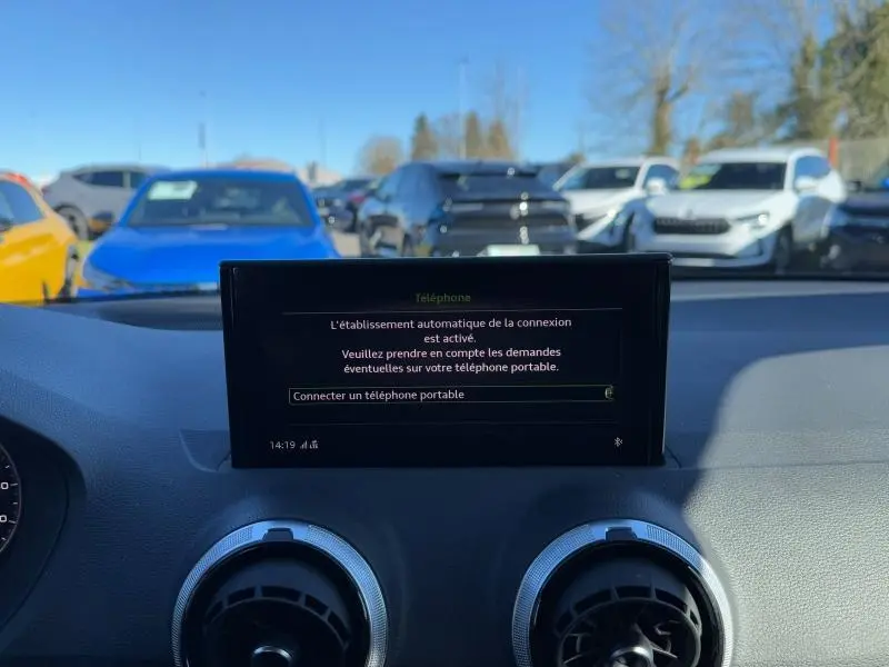 Vue intérieure du tableau de bord de l'Audi Q2 30 TDI S line 2024, écran central affichant la connexion téléphone.