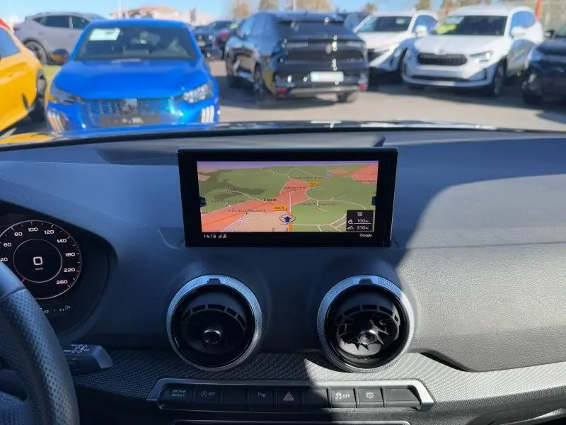 Vue intérieure du tableau de bord de l'Audi Q2 30 TDI 2024 avec écran GPS central et aérateurs ronds.