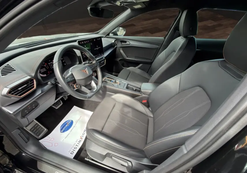 Vue intérieure côté conducteur de la CUPRA Formentor noire avec volant cuir, écran tactile central et sièges sport noirs.