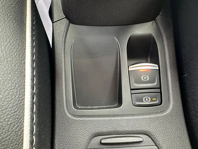 Gros plan sur la console centrale noire de la Renault Clio 2025, montrant les commandes de frein à main électronique et d'arrêt auto.