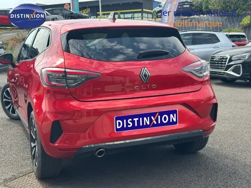 Vue 3/4 arrière d'une Renault Clio rouge flamme avec feux LED et sortie d'échappement chromée visible.