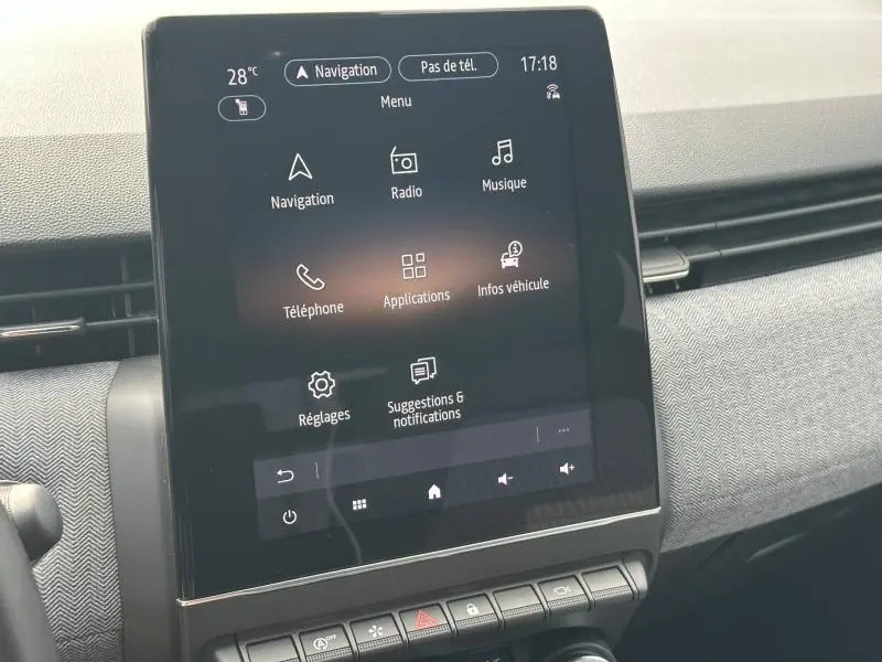 Vue rapprochée de l’écran tactile central du tableau de bord de la Renault Clio rouge Flamme, affichant le menu multimédia.