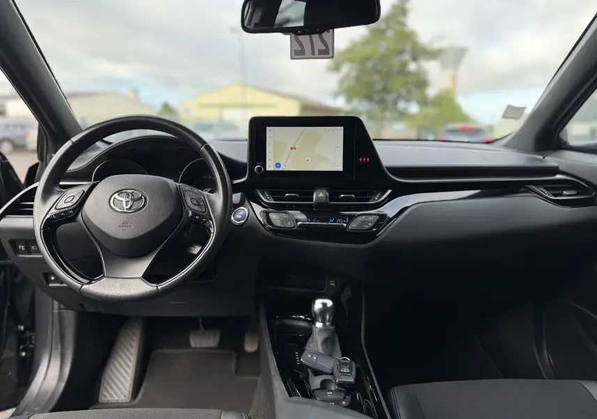 Vue intérieure avant du Toyota C-HR 1.8 hybrid gris atlas 2023, avec tableau de bord moderne et écran tactile central.