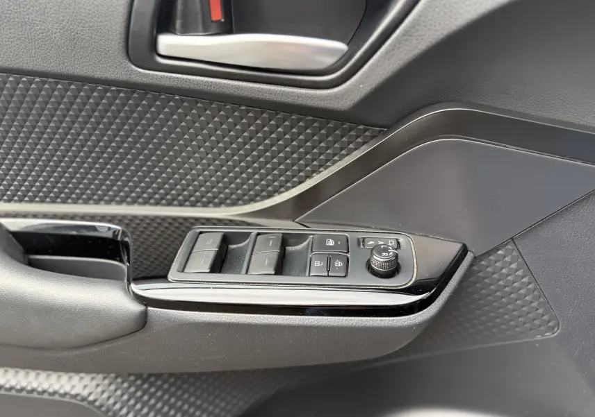 Détail de la porte côté conducteur du Toyota C-HR 1.8 hybrid gris atlas, avec commandes des vitres et réglage des rétroviseurs.