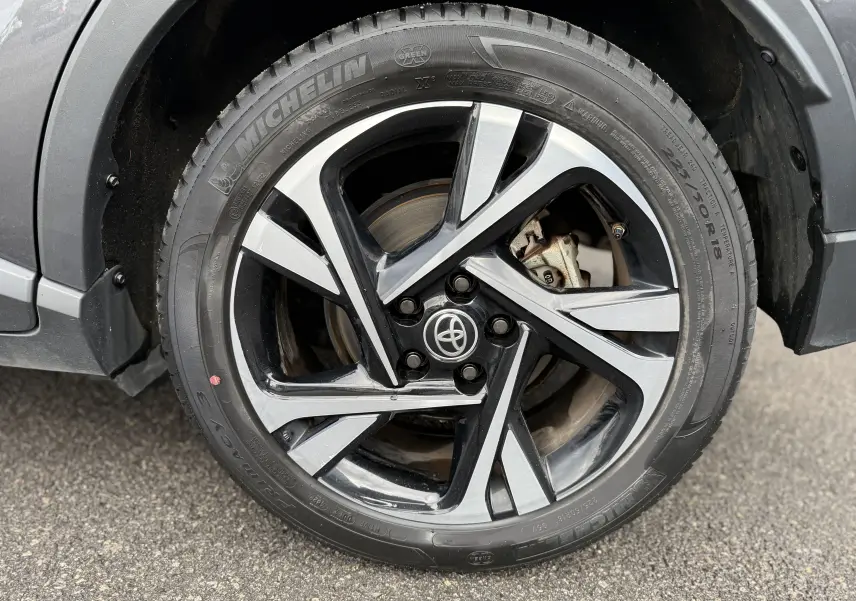 Gros plan sur la roue avant gauche du Toyota C-HR gris atlas, avec jante alliage bicolore et pneu Michelin.