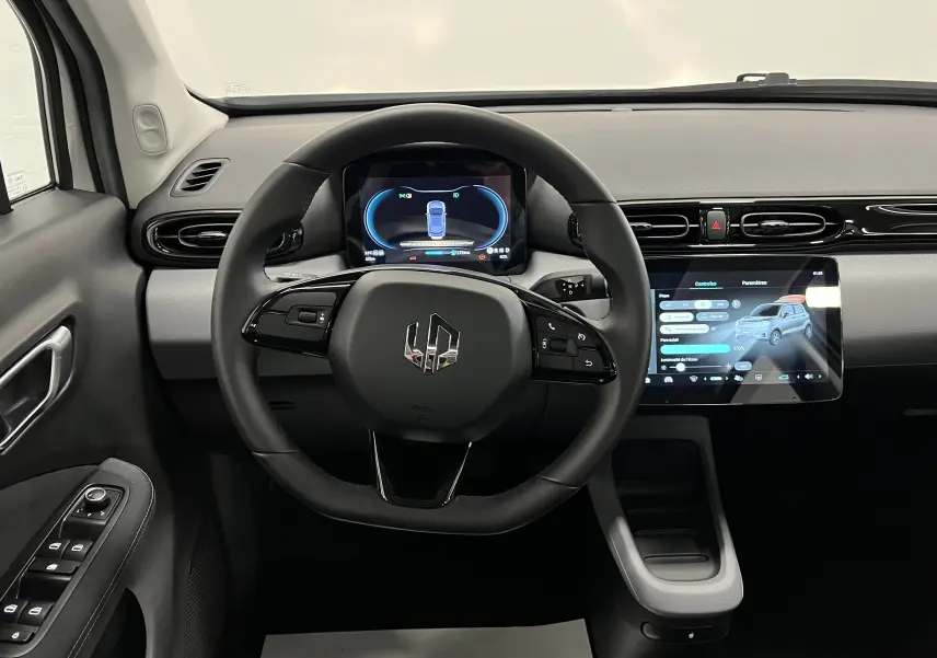 Vue intérieure centrée sur le volant et le tableau de bord numérique de la Dacia Spring blanche électrique avec écran tactile.