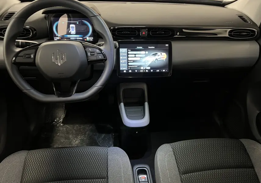 Intérieur du Dacia Spring blanc vu de face, tableau de bord moderne avec écran tactile central et volant multifonction.