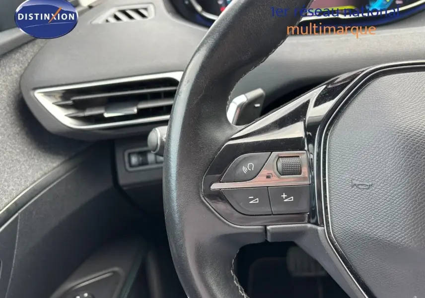 Gros plan sur le volant multifonction noir du Peugeot 3008 1.6 Hybrid 225, avec commandes audio et régulateur.