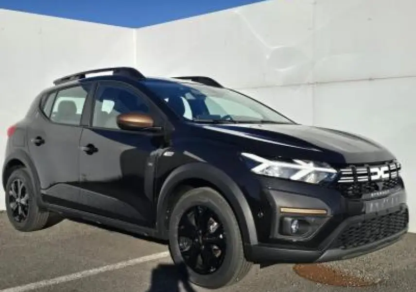 Dacia Sandero III Stepway noir nacré en 3/4 avant droit avec barres de toit et jantes noires distinctives.