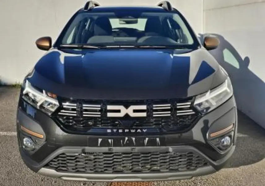 Vue avant d'une Dacia Sandero III Stepway 2025 noir nacré avec calandre marquée Stepway et barres de toit visibles.