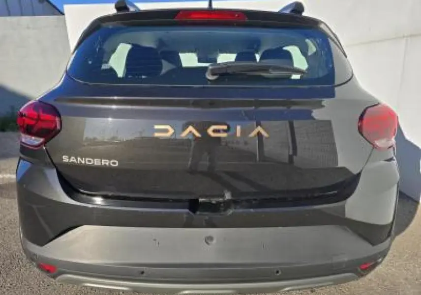 Vue arrière d'une Dacia Sandero III Stepway noire nacrée avec logo doré et feux arrière rouges.