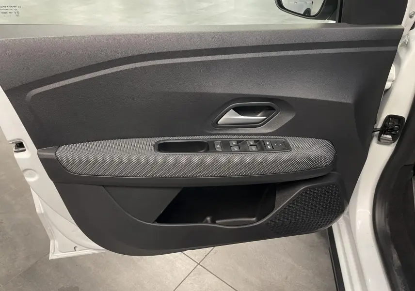 Vue côté intérieur de la porte avant gauche blanche du Dacia Sandero Stepway avec commandes de vitres et poignée grise.