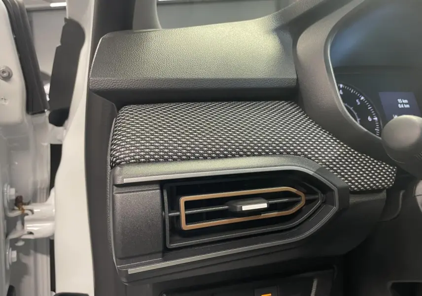 Détail de l'aérateur latéral avec insert brun cuivré sur tableau de bord noir du Dacia Sandero blanc glacier 2025.