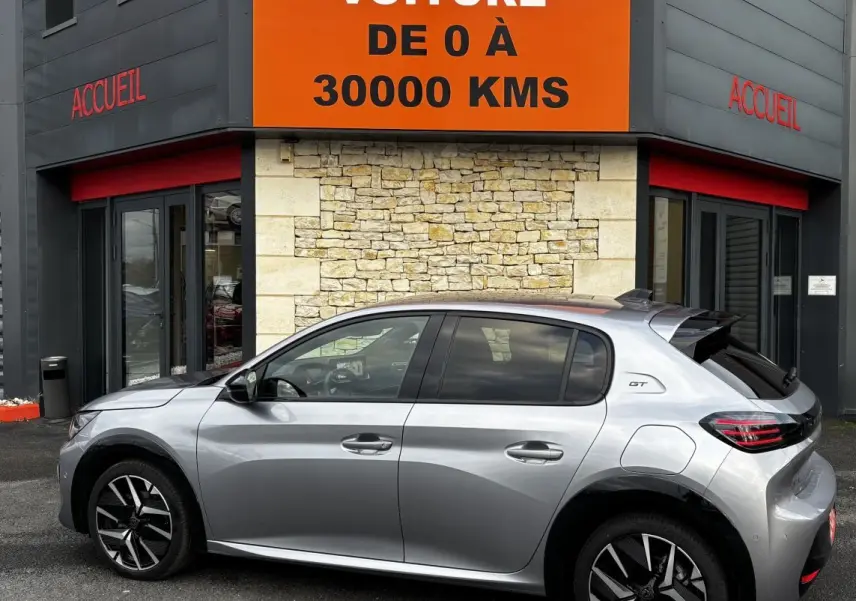 Peugeot 208 Hybrid 110 e-DCS6 GT gris clair vue de profil côté gauche, avec jantes noires et toit noir.
