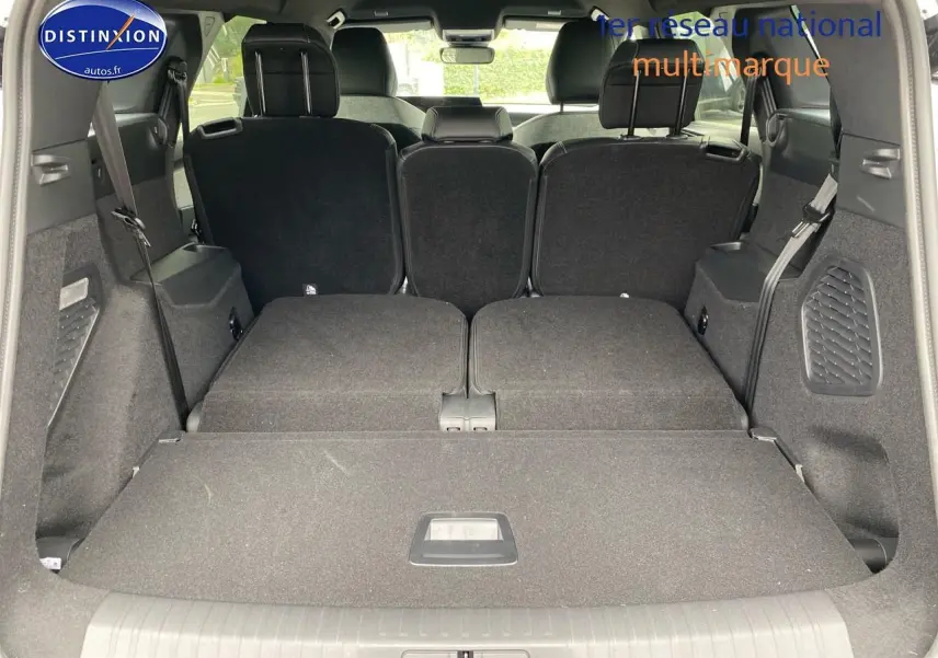 Vue arrière du coffre du Peugeot 5008 gris titane avec banquette arrière partiellement rabattue et sièges rang 3 relevés.