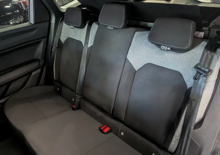 Vue intérieure des sièges arrière en tissu noir et gris du Dacia Bigster 2026, avec appuie-têtes et ceintures visibles.