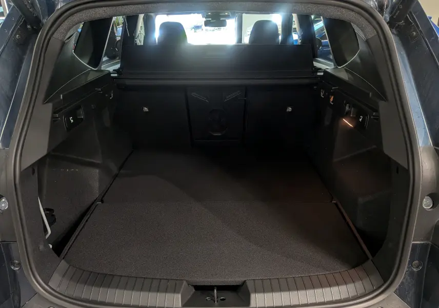Coffre ouvert du Dacia Bigster bleu indigo, vue arrière montrant un espace de chargement spacieux et bien éclairé.