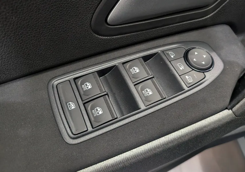 Panneau de commandes des vitres électriques et rétroviseurs sur la porte côté conducteur d'un Dacia Bigster bleu indigo.