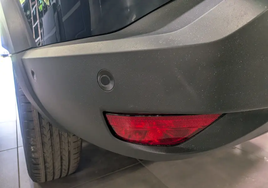 Gros plan sur le pare-chocs arrière droit bleu indigo du Dacia Bigster 2026 avec feu rouge et capteurs de recul.