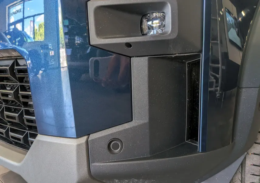 Gros plan sur l’angle avant droit bleu indigo du Dacia Bigster 2026, mettant en valeur le feu antibrouillard et la grille noire.