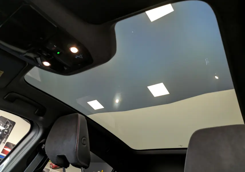 Vue intérieure du toit panoramique avec éclairage LED et appuie-tête en cuir noir du Renault Rafale gris schiste.