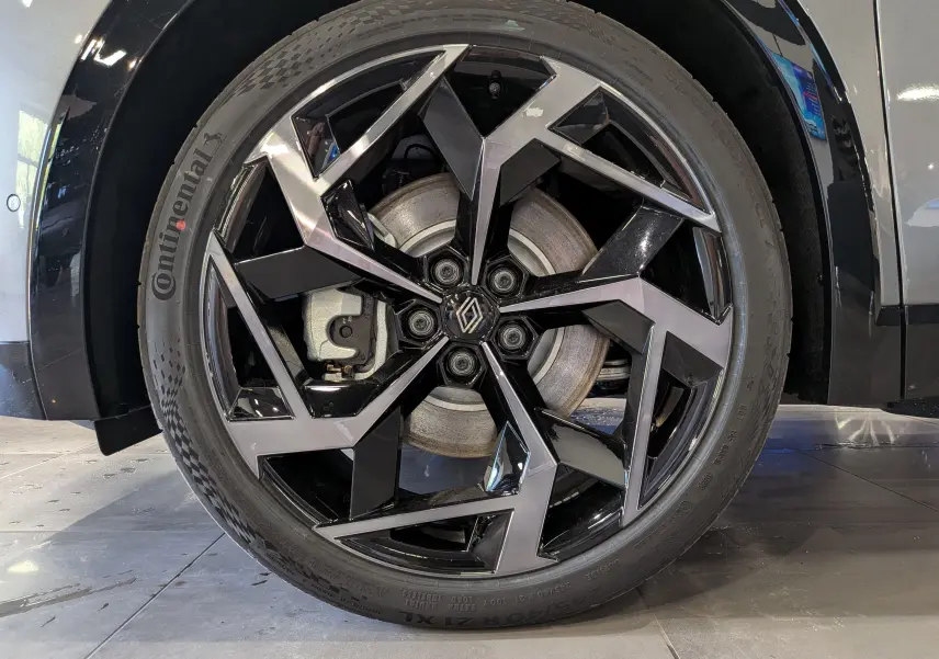 Gros plan sur la jante avant droite du Renault Rafale gris schiste, avec un design géométrique noir et argenté distinctif.