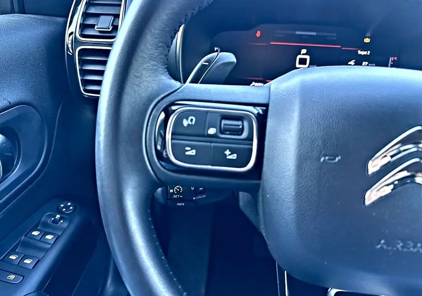 Gros plan sur le volant cuir multifonction noir côté gauche du Citroën C5 Aircross 2025 avec commandes intégrées.