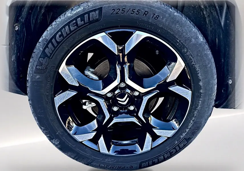 Gros plan sur la jante alu noire et chromée avec logo Citroën d’un pneu Michelin d’un Citroën C5 Aircross noir.