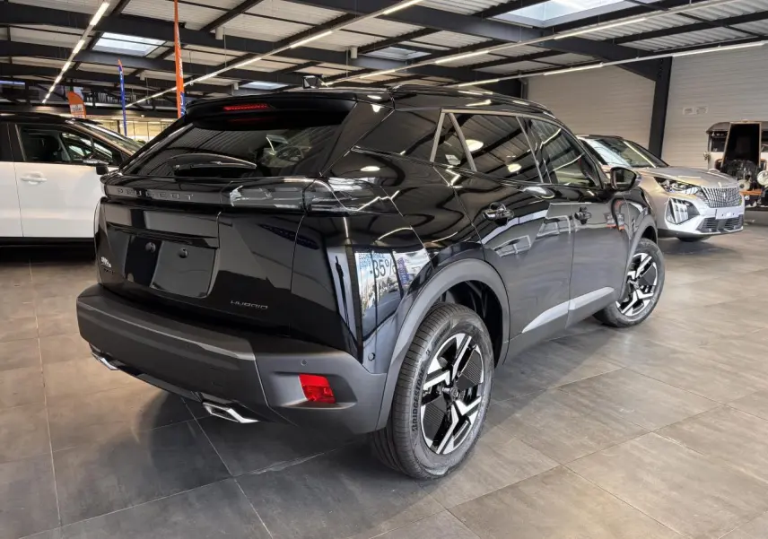 Peugeot 2008 hybride noire vue 3/4 arrière droit en intérieur avec jantes bi-ton et feux LED griffés.