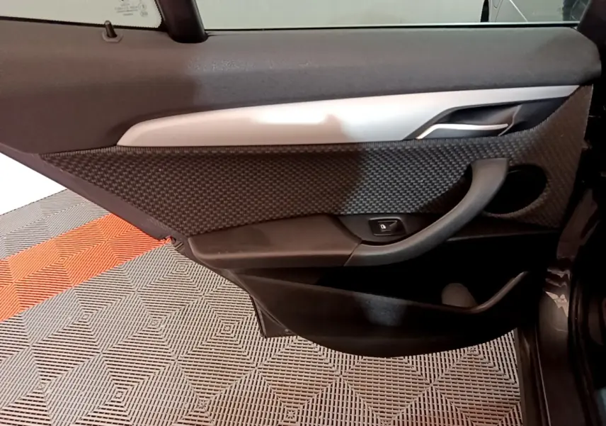 Détail de la porte arrière droite de BMW X2 hybride rechargeable, avec garniture noire texturée et poignée intégrée.