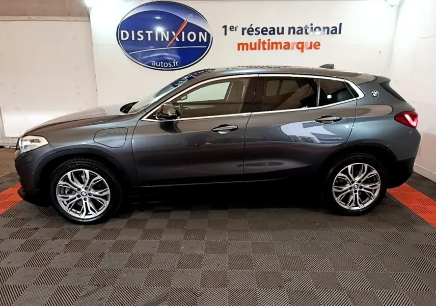 Profil droit d’un BMW X2 xDrive25e gris métallisé hybride rechargeable, avec jantes alliage et logo BMW sur l’aile arrière.