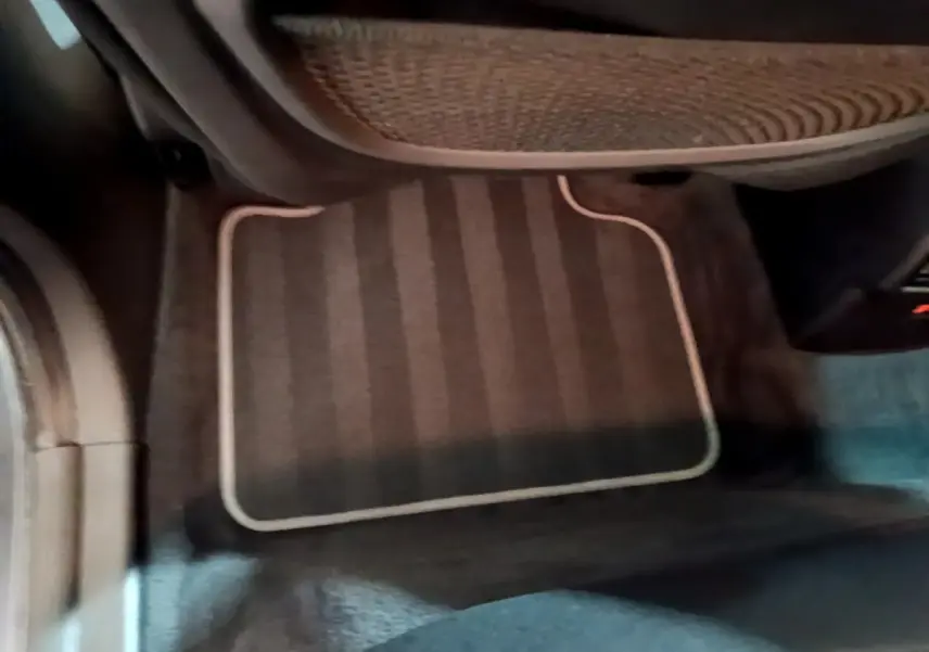 Vue intérieure du tapis de sol côté passager avant d'une BMW X2 hybride rechargeable, couleur sombre avec surpiqûres claires.