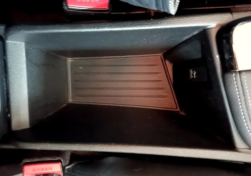 Gros plan sur le rangement central noir de la BMW X2 hybride rechargeable, avec bouton USB visible à droite.