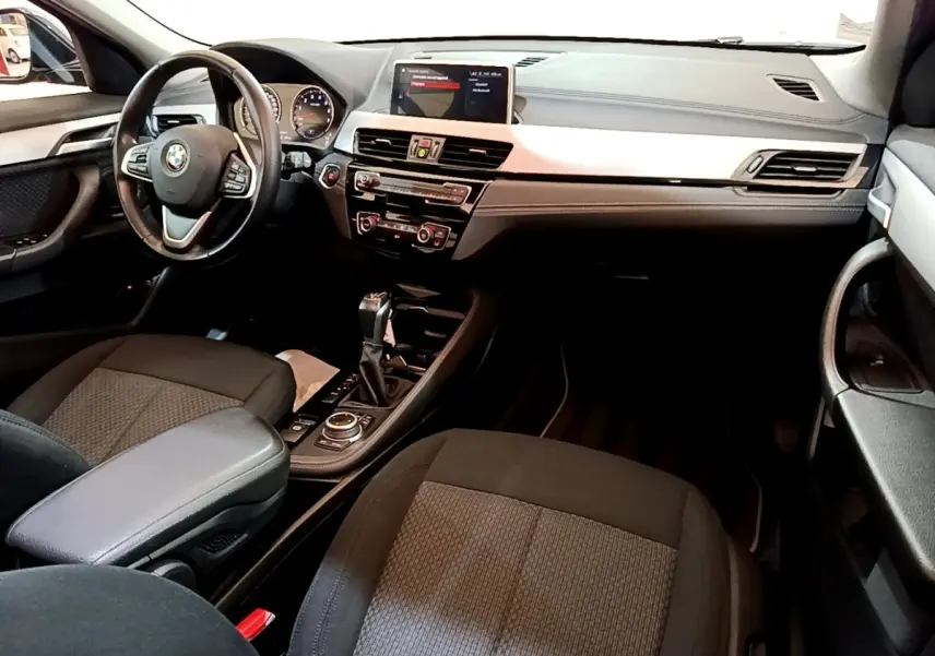 Intérieur BMW X2 xDrive25e 2020 vu de l'avant droit, tableau de bord noir avec écran tactile central et volant multifonctions.