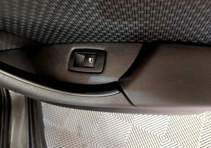 Bouton de commande de lève-vitre sur la porte intérieure en cuir noir du BMW X2 xDrive25e, vue rapprochée.