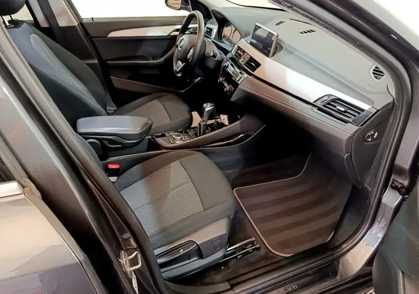 Vue intérieure côté conducteur de la BMW X2 hybride rechargeable 2020, sièges tissu gris et tableau de bord moderne.