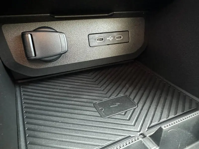 Gros plan sur la console centrale du Dacia Duster 2025, montrant les ports USB et un espace de recharge sans fil noir.